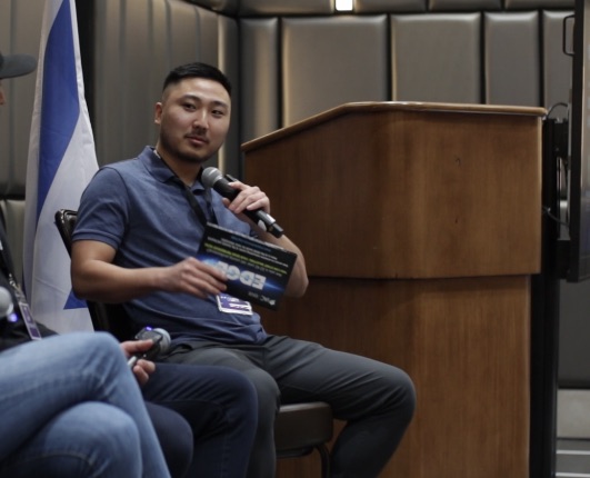 Kyler on a conference panel with a microphone